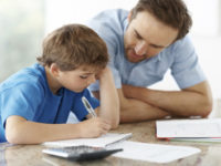 Young man assisting his little son with some home work